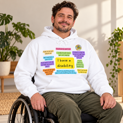 Lifestyle mock-up of a wheelchair user wearing the white I Have a Disability front-print hoodie; logo composited from a photograph of the actual printed design.